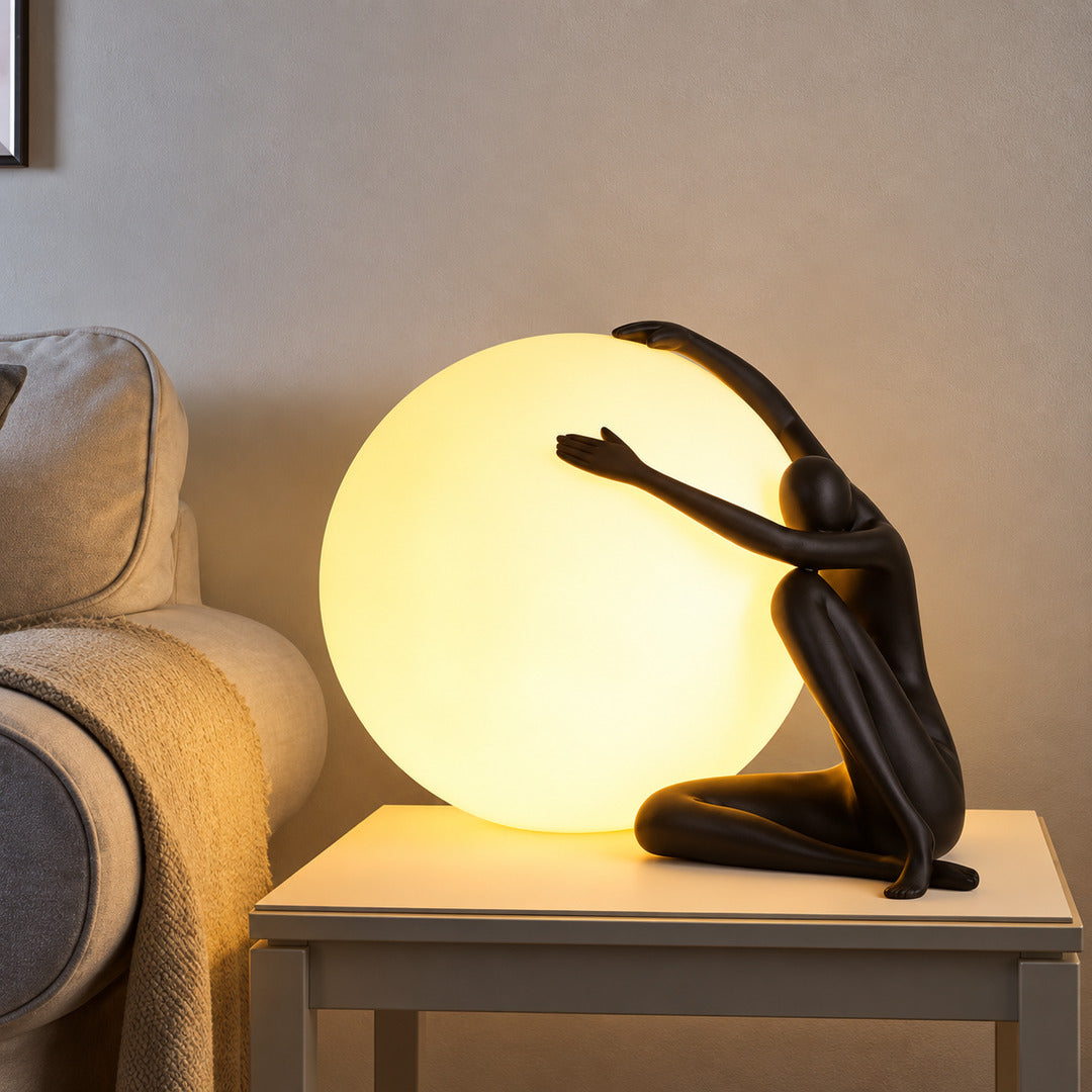 Musa sculpture table lamp casting a warm glow on a living room side table