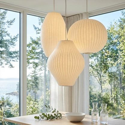 Nelson style bubble Cigar drum pendant pair above modern kitchen island Mid Century white spun polymer architectural warm glow interior