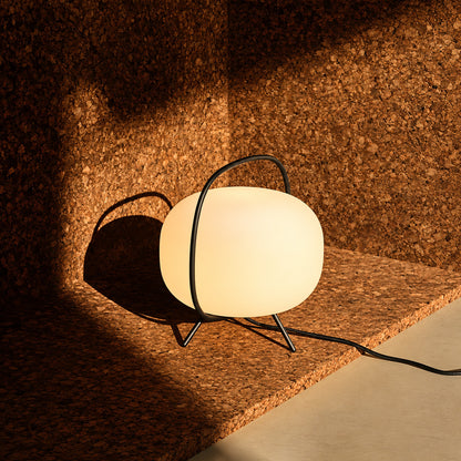 Nomade glass table lamp glowing softly on a styled bookshelf