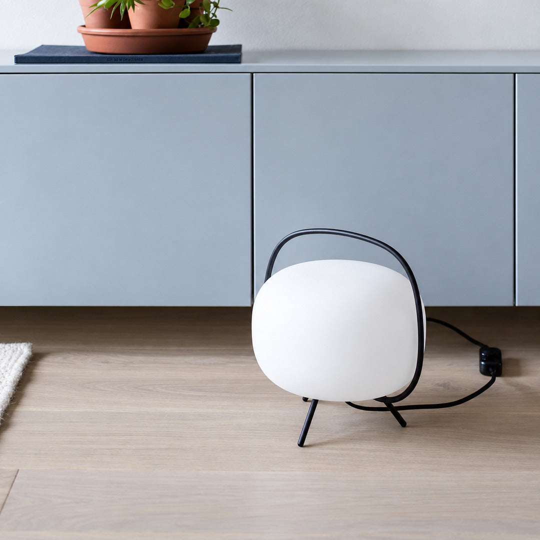 Nomade glass table lamp welcoming guests on an entryway console with a warm glow