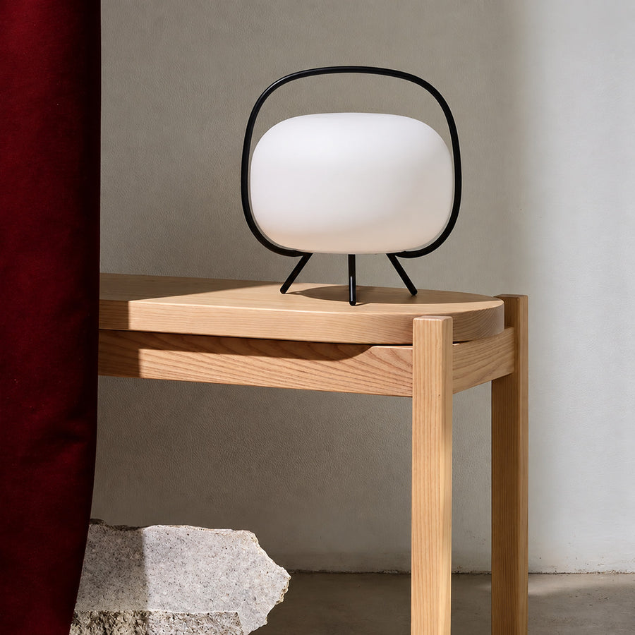 Nomade glass table lamp casting a soft warm glow on a living room side table