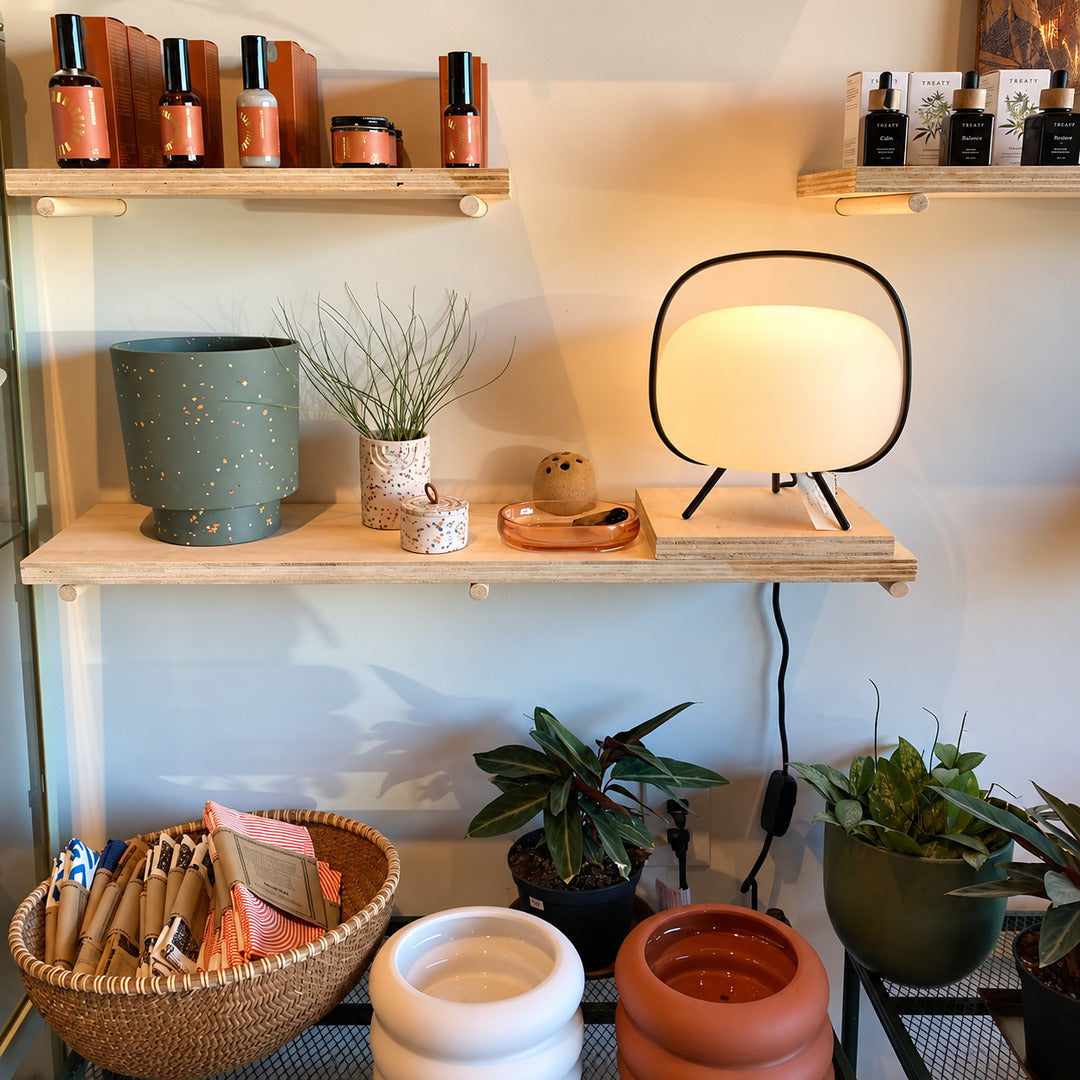 Nomade glass table lamp glowing softly on a styled bookshelf