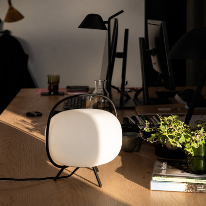Nomade glass table lamp adding a soft warm glow to a home office desk