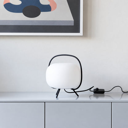 Nomade glass table lamp casting a soft warm glow on a living room side table