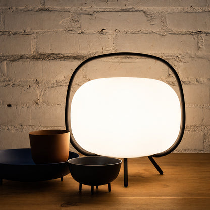 Nomade glass table lamp adding a soft warm glow to a home office desk