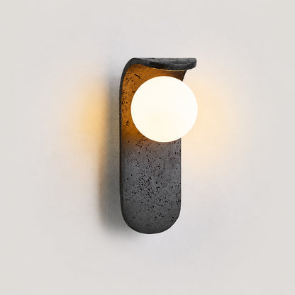 Notte travertine wall sconce illuminated warm glow black travertine stone orb wall white background