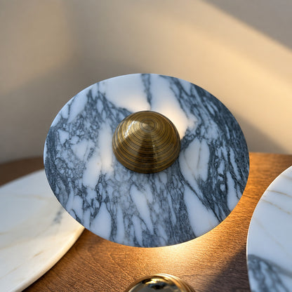 Detail of the round stone disc and slim metal edge of the Orbe marble wall sconce