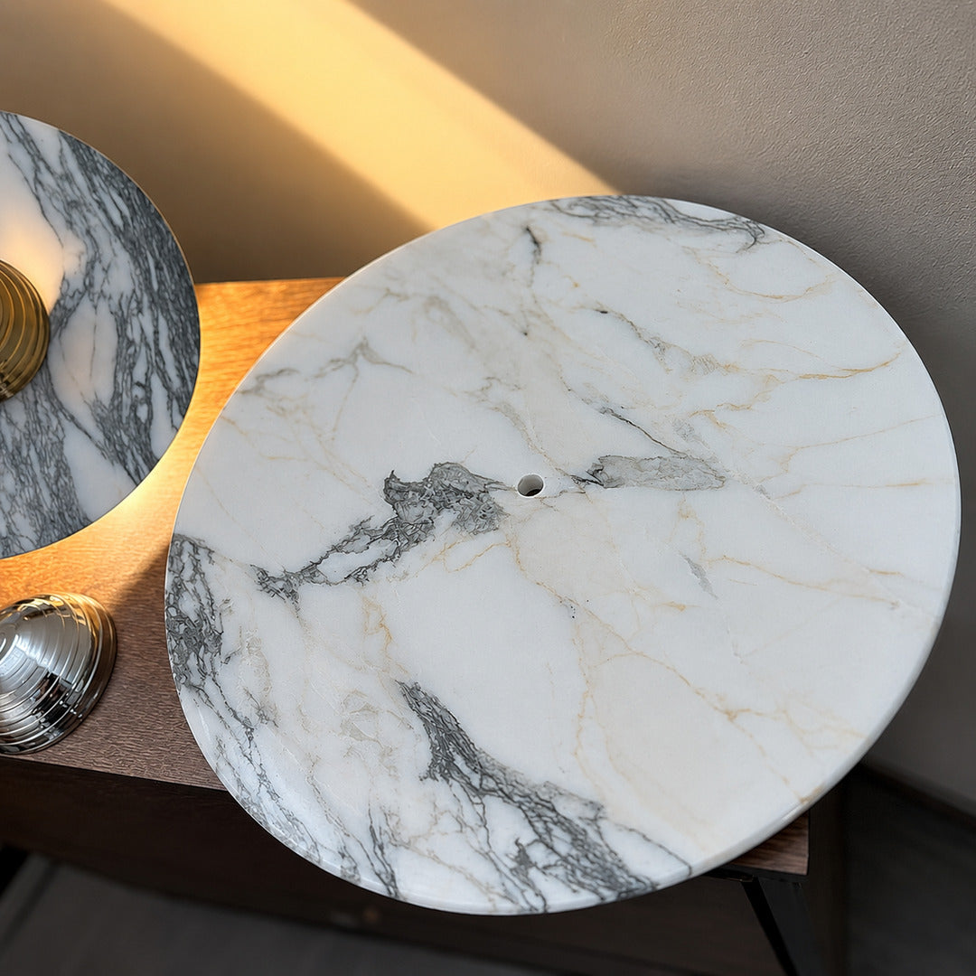 Close-up of the natural marble disc on the Orbe wall sconce showing its unique veining, different on every piece