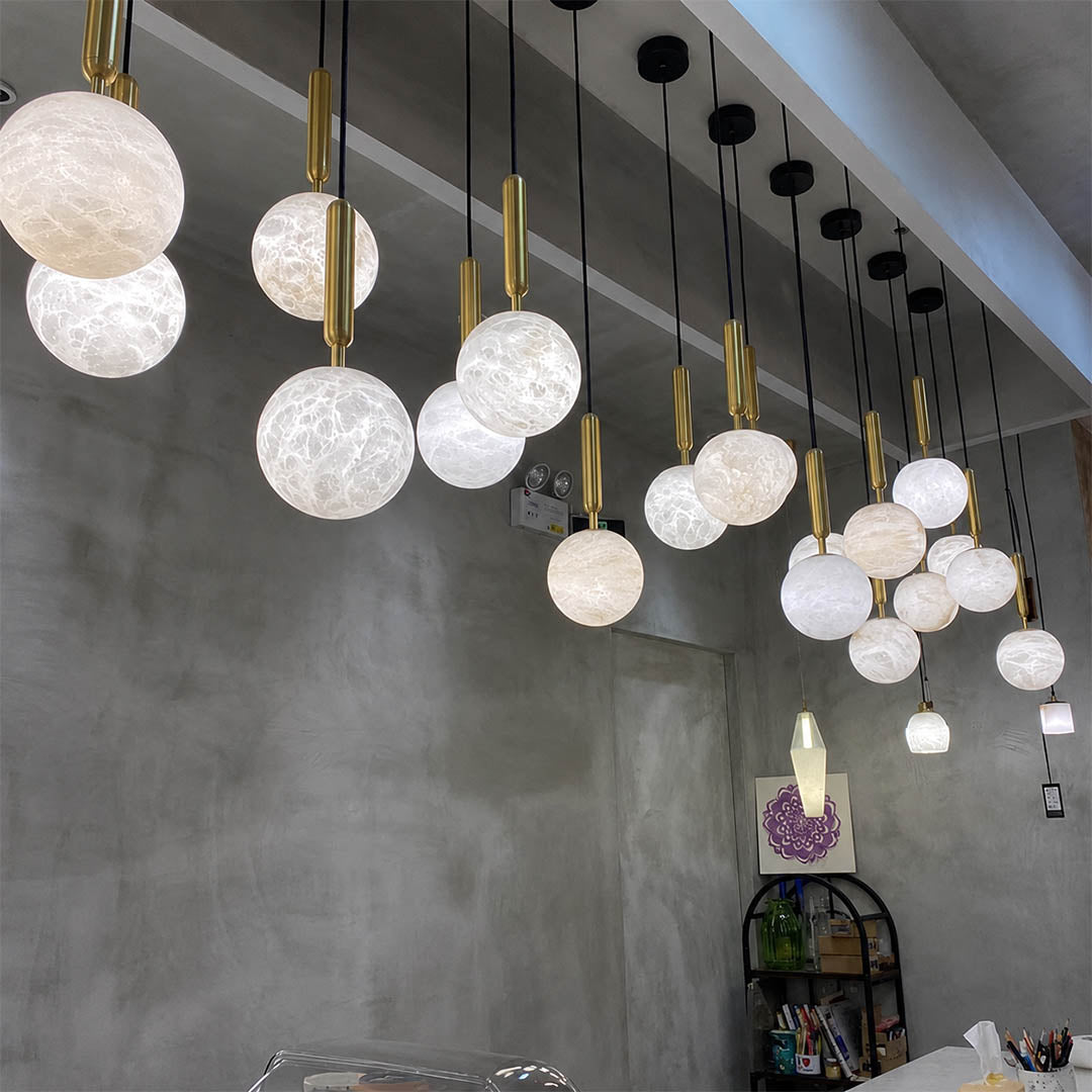 Orbita alabaster globe pendant light boutique hotel lobby grand galactic cluster natural stone brass quiet luxury hospitality American commercial interior
