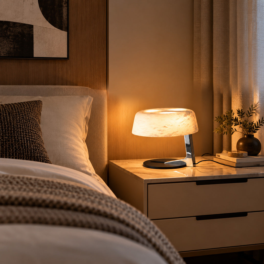 Orbita alabaster table lamp casting a soft glow on a bedside table