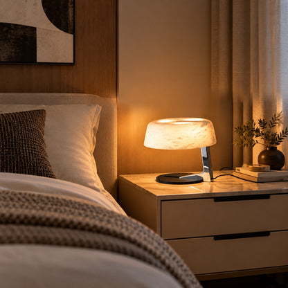 Orbita alabaster table lamp casting a soft glow on a bedside table