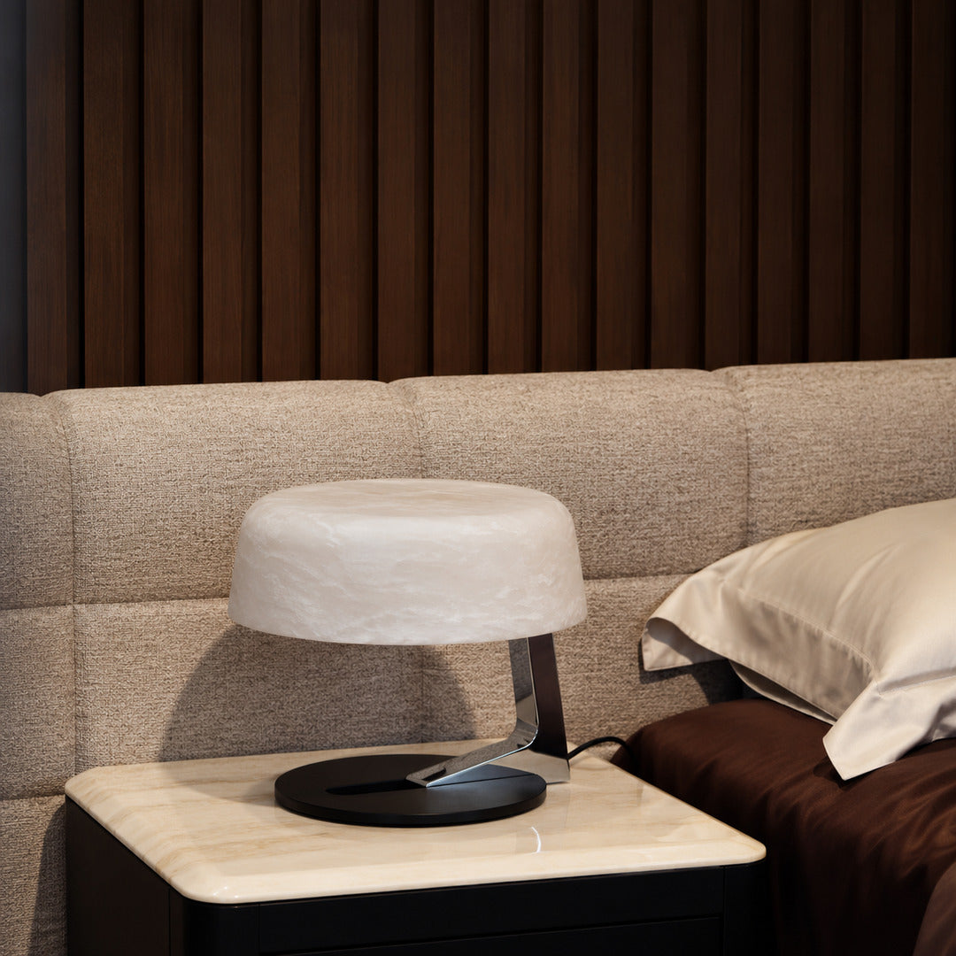 Orbita alabaster table lamp casting a soft glow on a bedside table