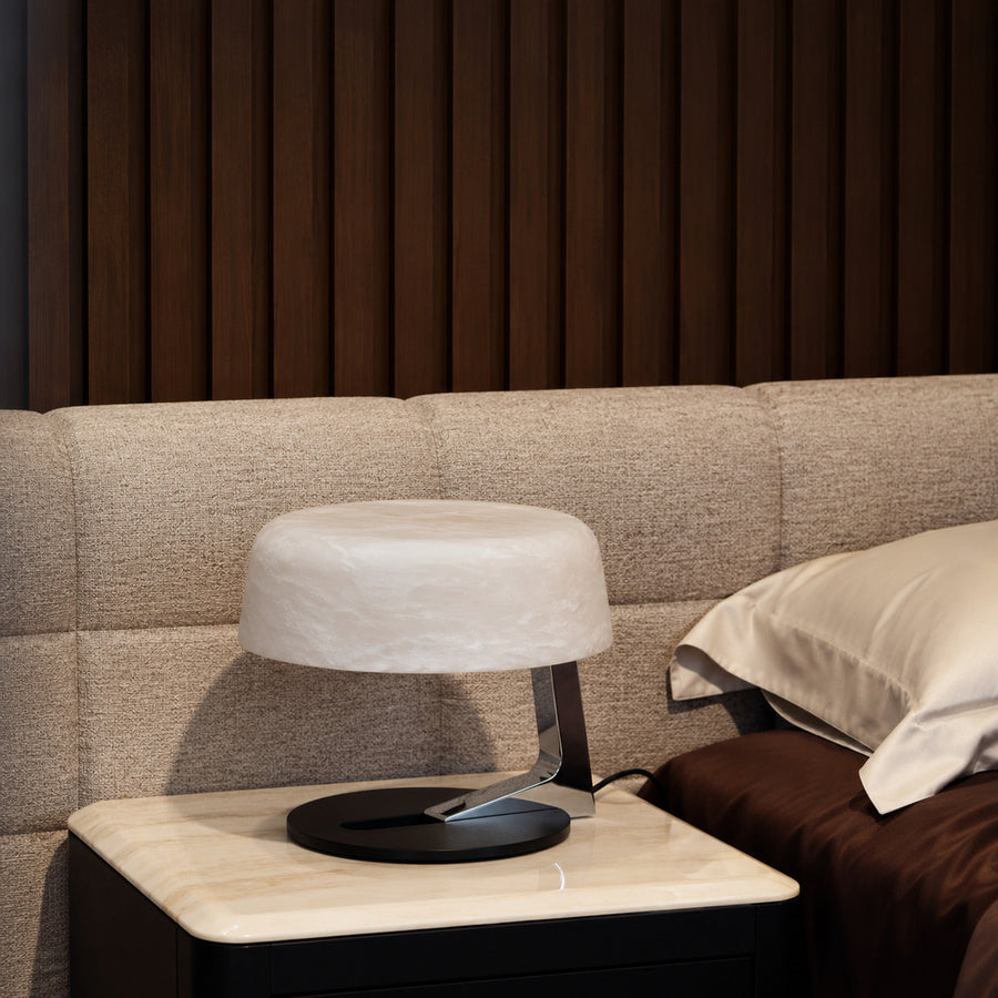 Orbita alabaster table lamp casting a soft glow on a bedside table