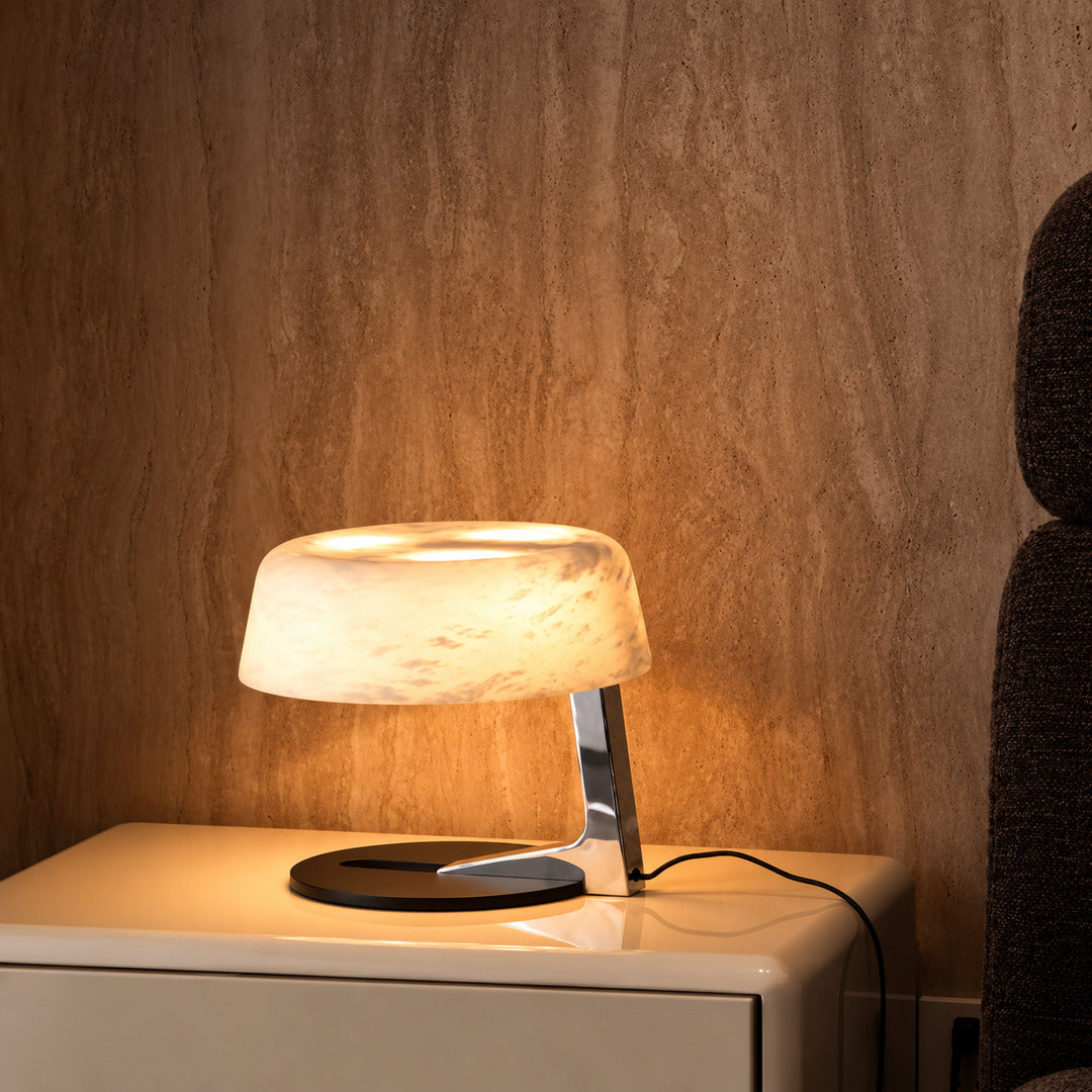 Orbita alabaster table lamp casting a soft glow on a bedside table