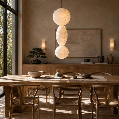 Sculptural Ori Lantern Series Paper Pendant Lamp centered over an elegant wooden dining table setup by Stuber Lighting.