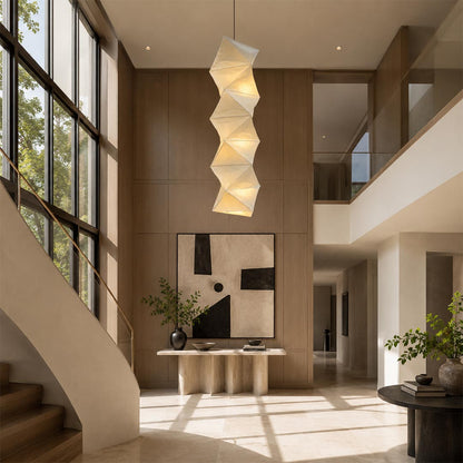 Long vertical Washi Paper L8 Pendant Lamp hanging in a luxurious high-ceiling foyer with a modern staircase by Stuber Lighting.