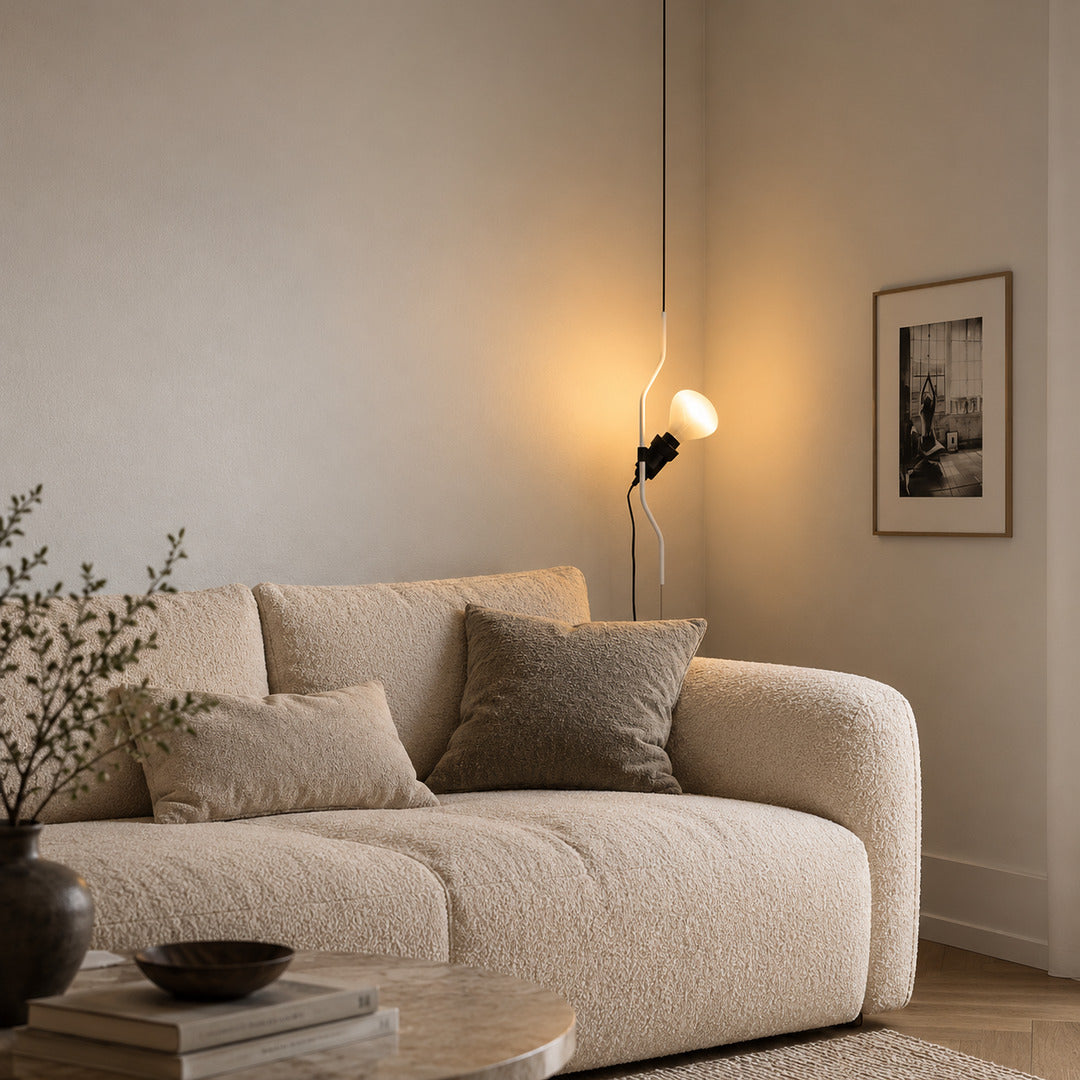 Black Parentheses lamp with its spotlight lowered beside a sofa arm for evening reading
