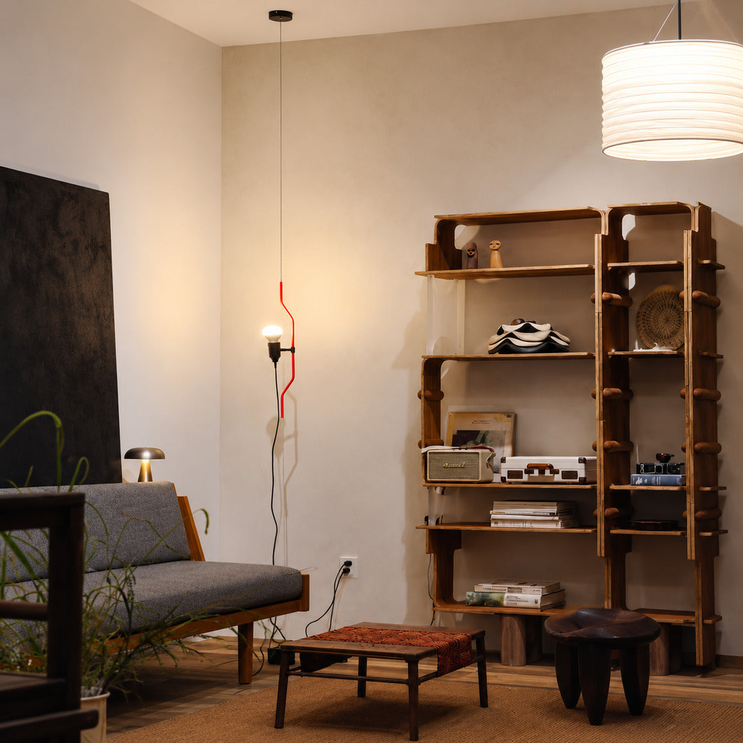 Black Parentheses lamp with its spotlight lowered beside a sofa arm for evening reading
