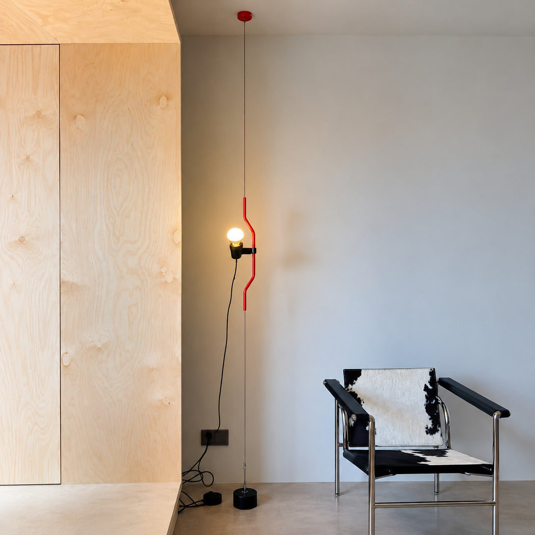 Red Parentheses floor to ceiling lamp lighting an armchair in a quiet reading nook