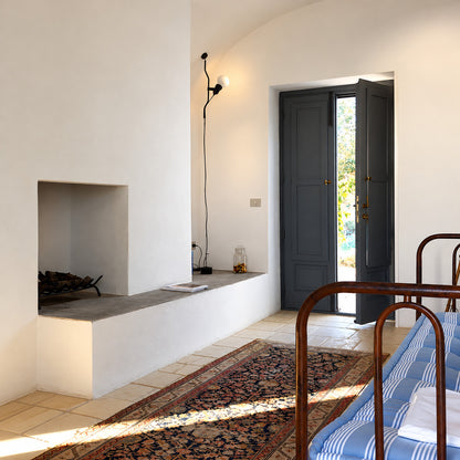 White Parentheses floor to ceiling lamp beside an entryway bench as a sleek accent light