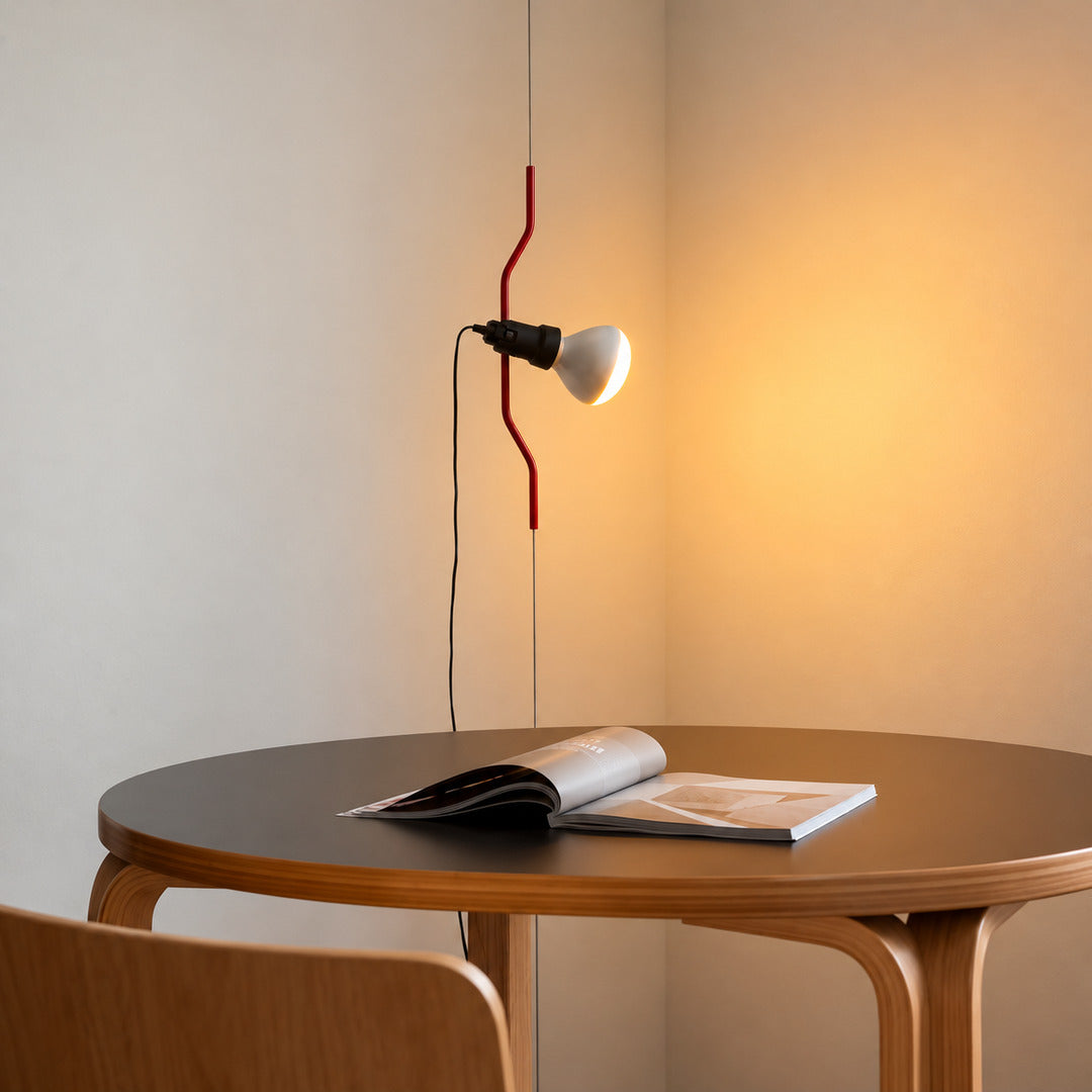 Red Parentheses floor-to-ceiling lamp beside a dining table casting a focused warm pool of light