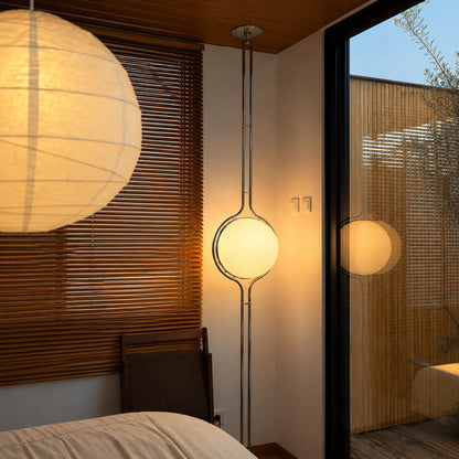 Silver Pendolo tension pole lamp in a bedroom corner next to a reading chair