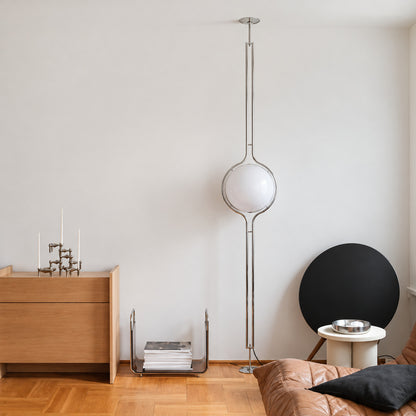 Silver Pendolo pole lamp standing behind a low sofa as a sculptural accent light
