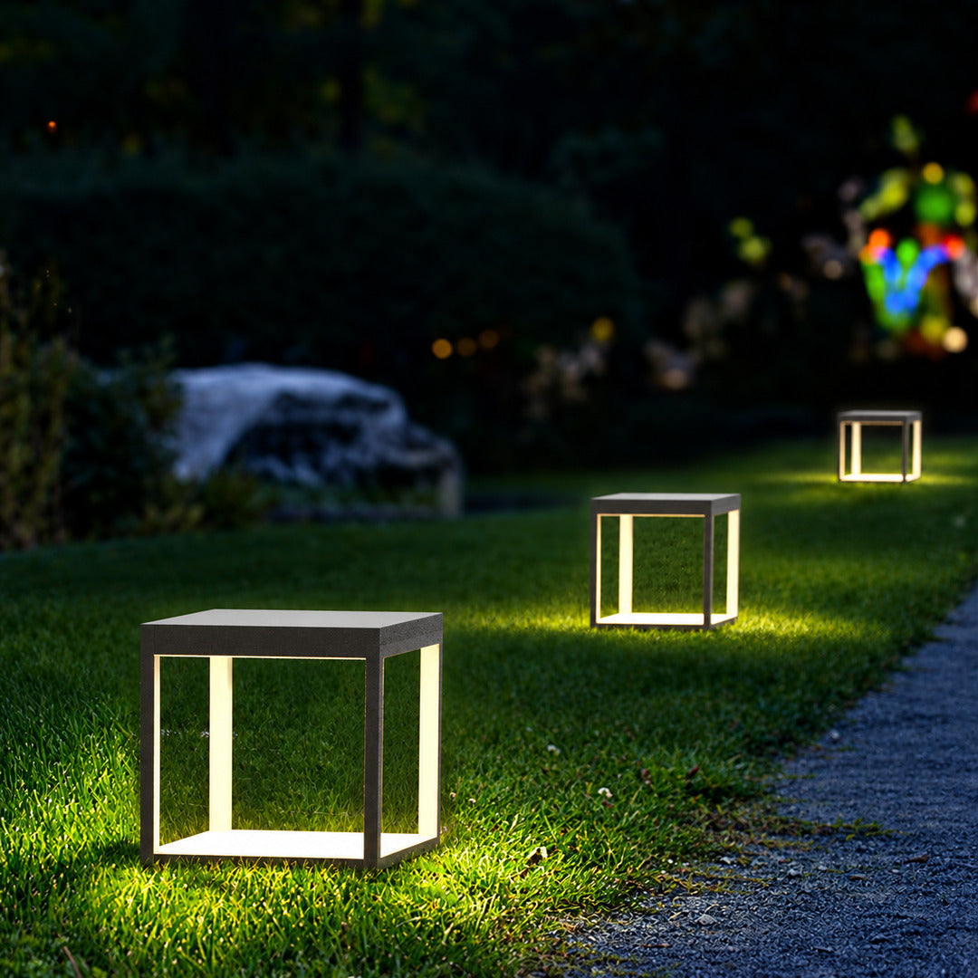 Quadro outdoor post lights lining a garden bed with a warm modern glow at dusk