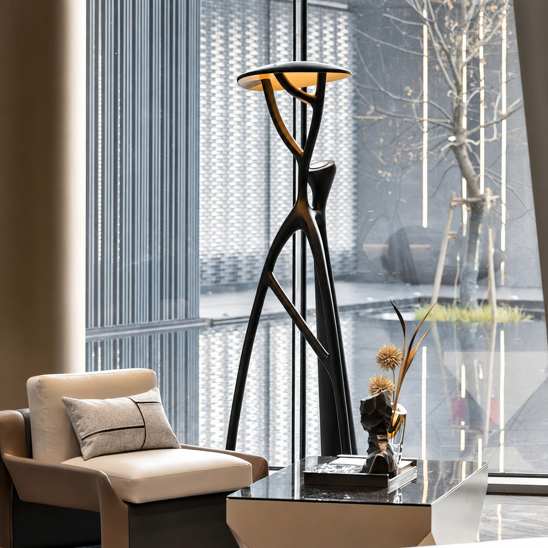 Ramo tree sculpture floor lamp casting a soft warm glow over a corner reading chair