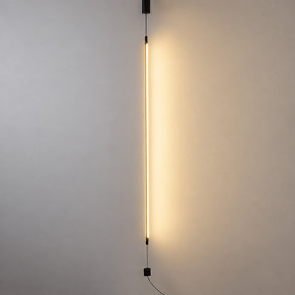 Riga floor to ceiling lamp with a slim black LED tube glowing warm in a modern living room corner