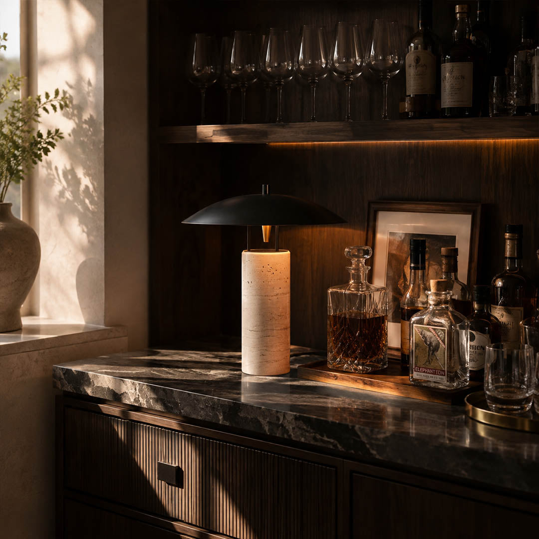 Sabbia travertine table lamp illuminated evening travertine warm glowing black shade cozy natural American home lifestyle interior