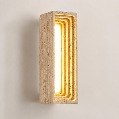 Sasso travertine wall sconce illuminated warm glow natural travertine stone column wall white background