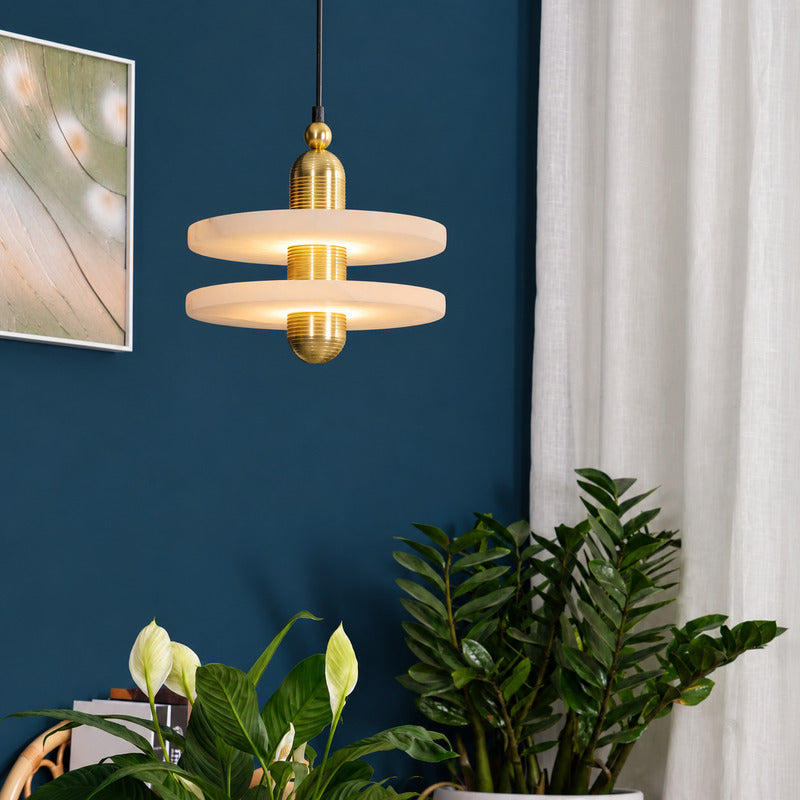 Warm light escaping above and below the alabaster disc of the Saturno pendant, washing the ceiling and table