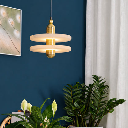 Warm light escaping above and below the alabaster disc of the Saturno pendant, washing the ceiling and table