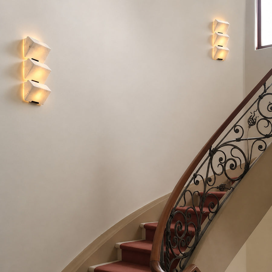 Scala alabaster wall sconce lighting a staircase wall with a soft stepped natural-stone glow
