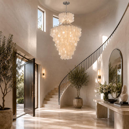 Large Wabi-Sabi tier chandelier hanging above a grand curved staircase in a bright, high-ceiling entryway.