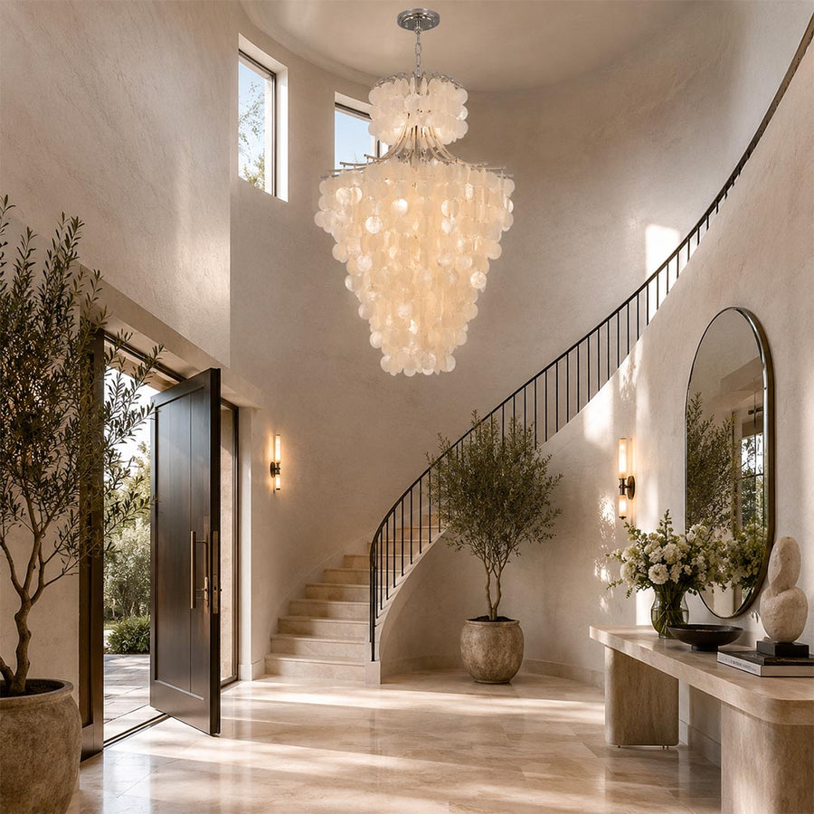 Large Wabi-Sabi tier chandelier hanging above a grand curved staircase in a bright, high-ceiling entryway.