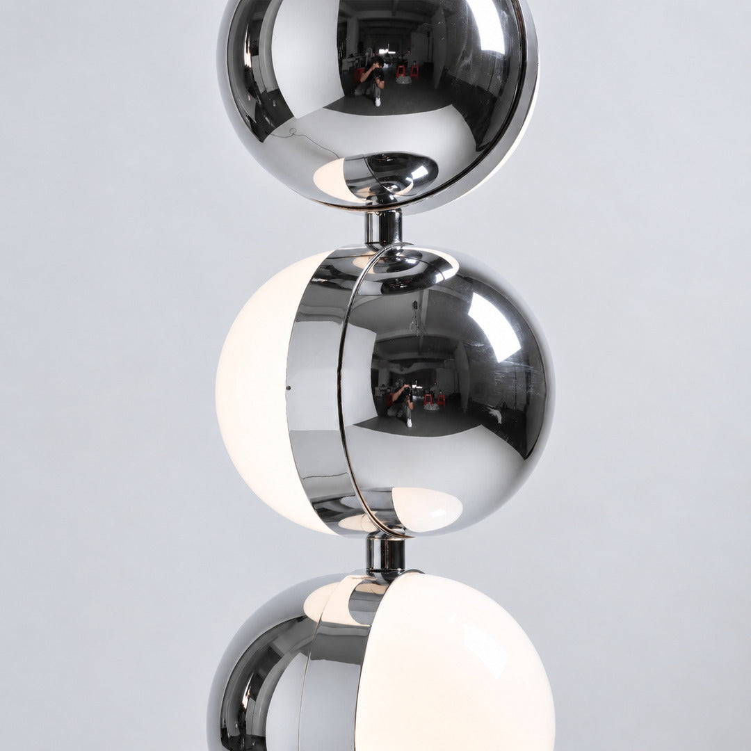 Polished chrome finish of the Slancio floor lamp reflecting the light of a modern room