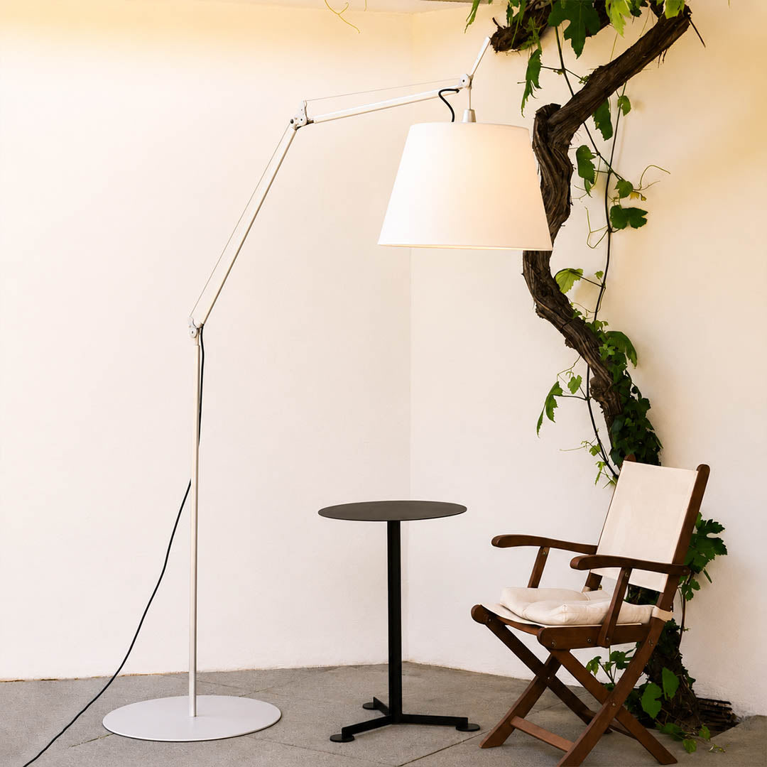 Snodo floor lamp positioned beside a leather armchair in a corner reading nook with a stack of books