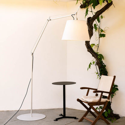 Snodo floor lamp positioned beside a leather armchair in a corner reading nook with a stack of books