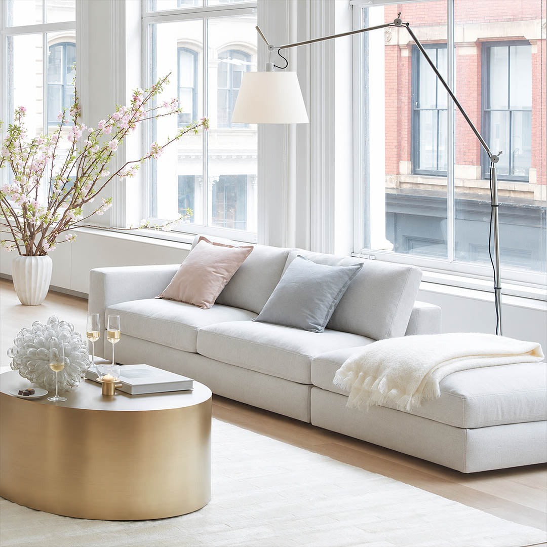 Tall Snodo floor lamp arcing over a linen sectional in a modern American living room, warm evening reading light