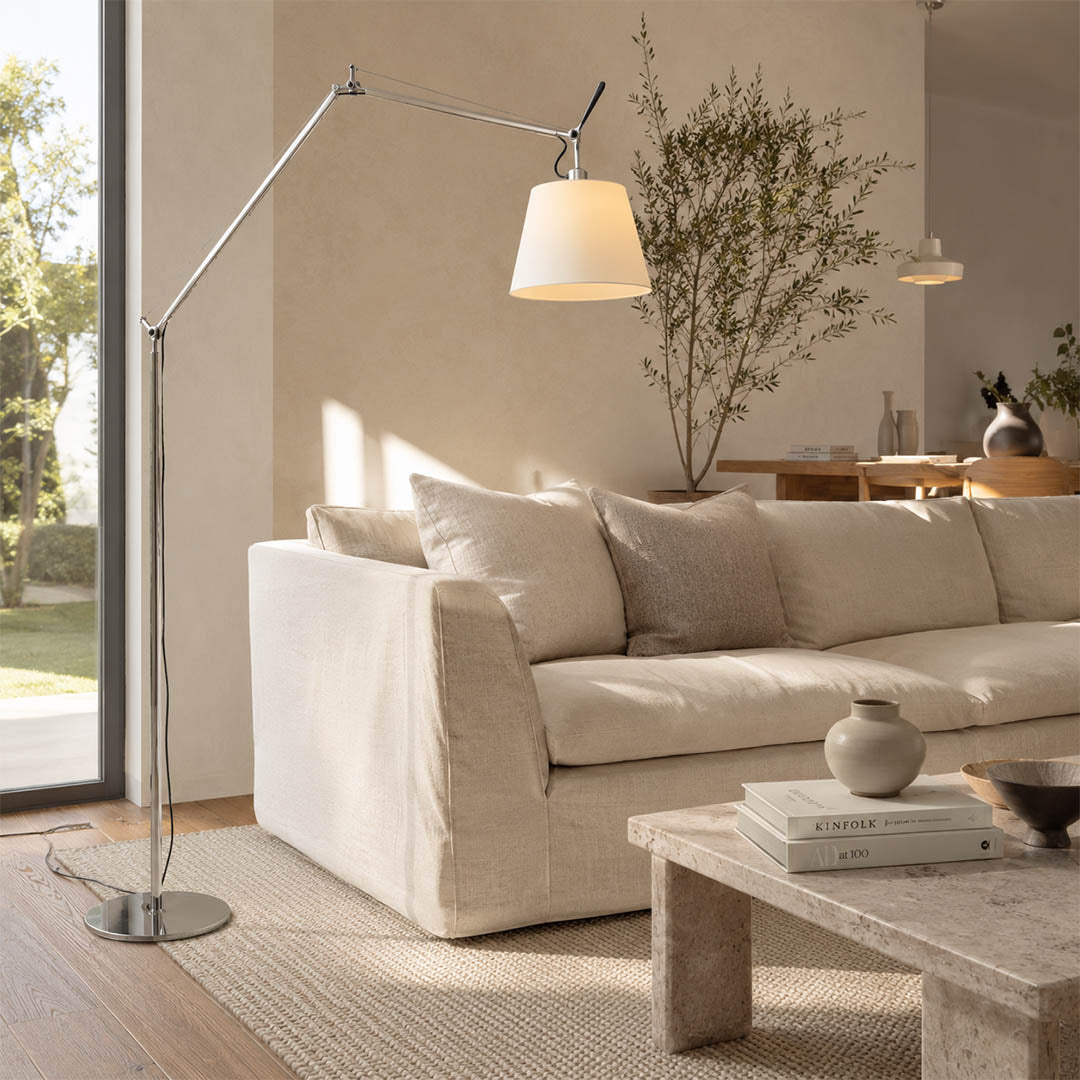 The 95.7-inch Snodo floor lamp arcing over the back of a sofa in an American living room, delivering direct reading light without a side table