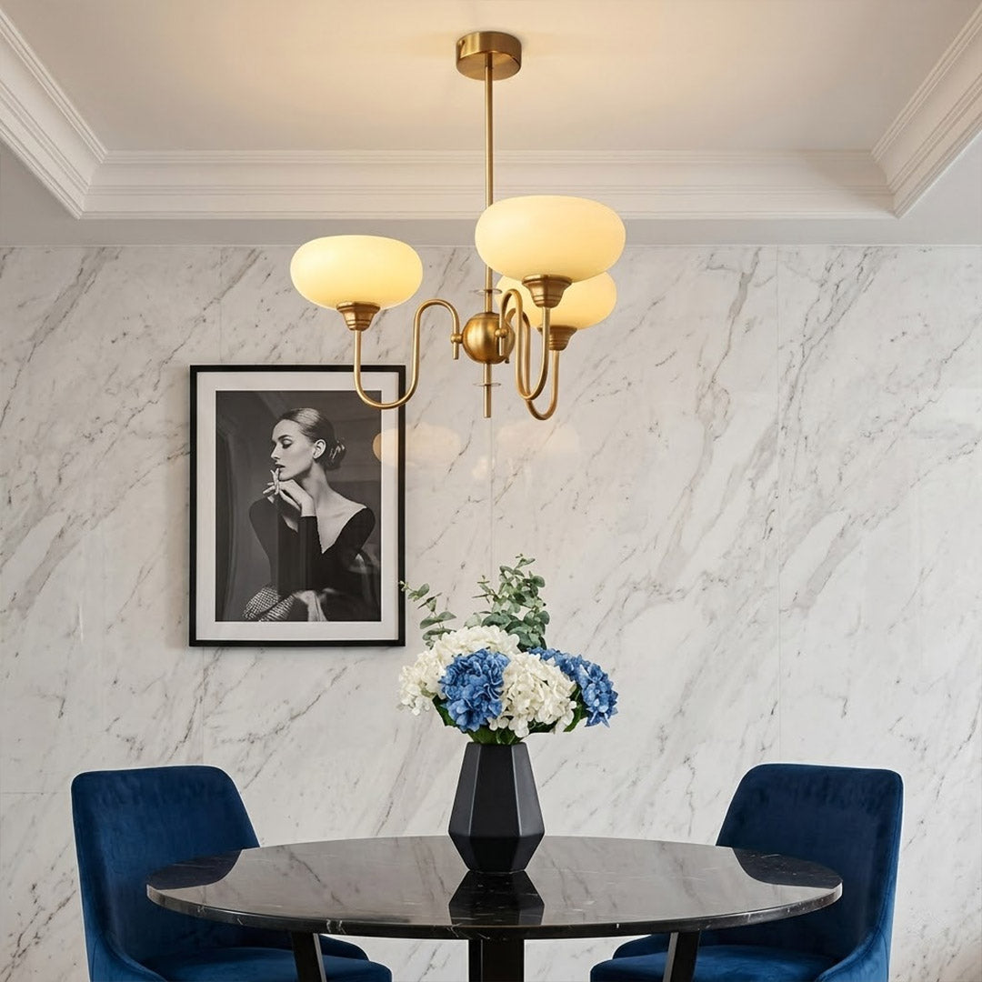 Solari cream glass chandelier above dining table warm amber gold light organic modern interior