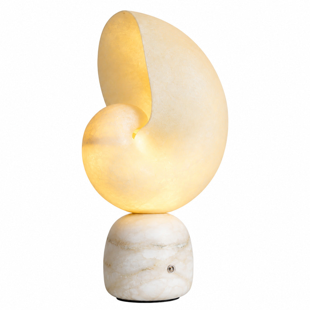 Spira alabaster table lamp shaped like a spiral seashell glowing warm on a nightstand