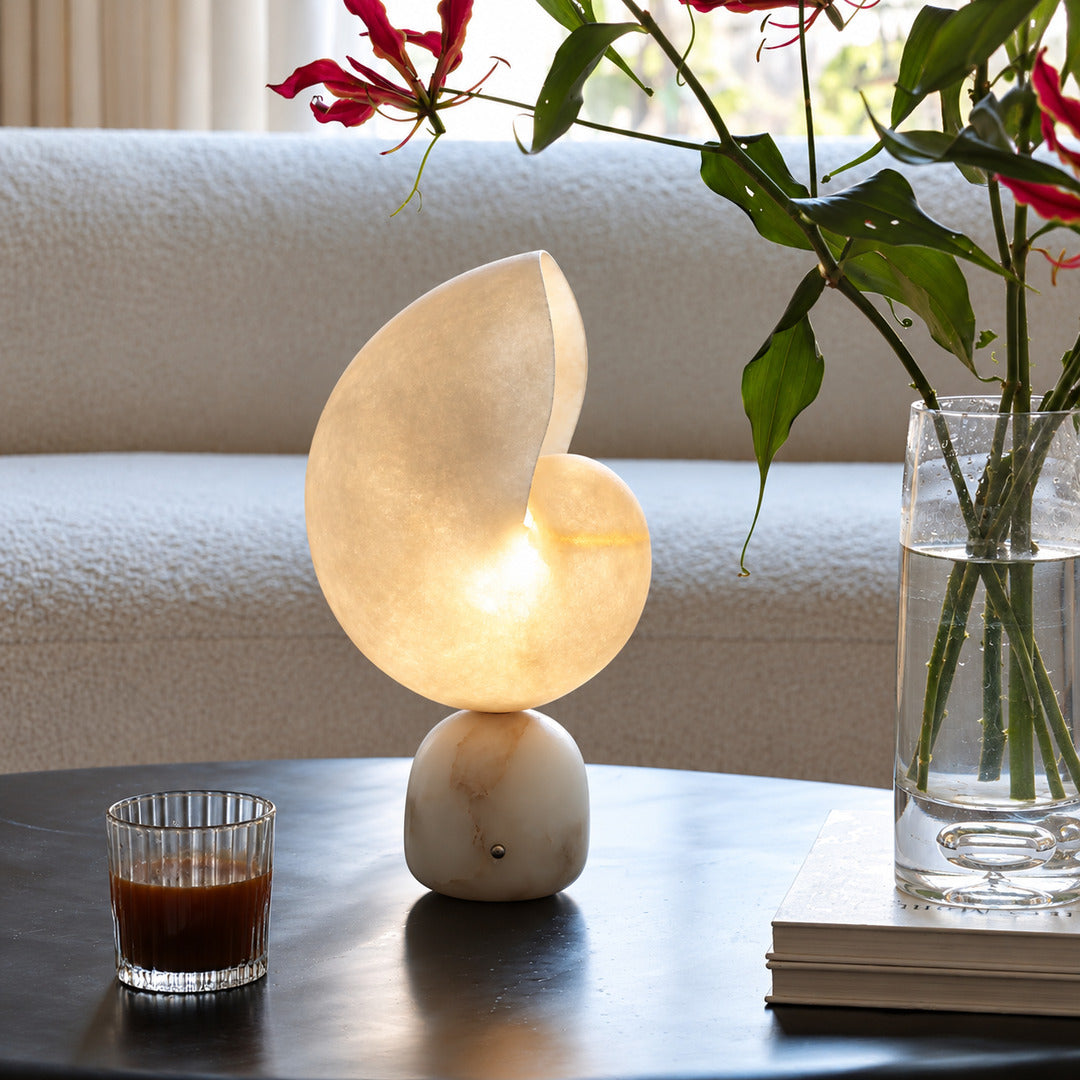 Spira alabaster lamp beside a potted plant on a living room side table