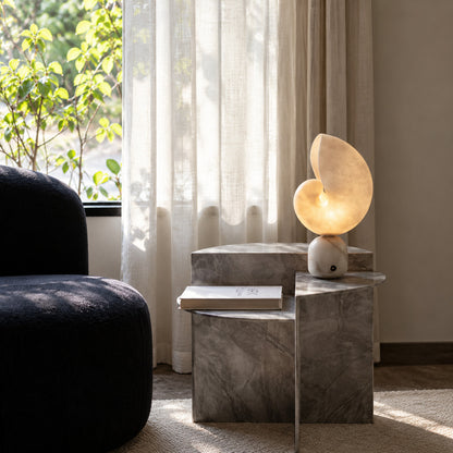 Spira alabaster lamp beside a potted plant on a living room side table