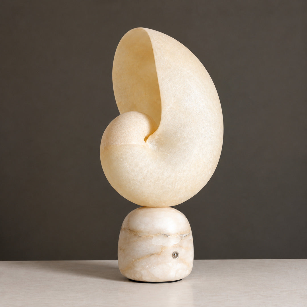 Spira spiral shell table lamp carved from natural alabaster with a solid stone base on a white background