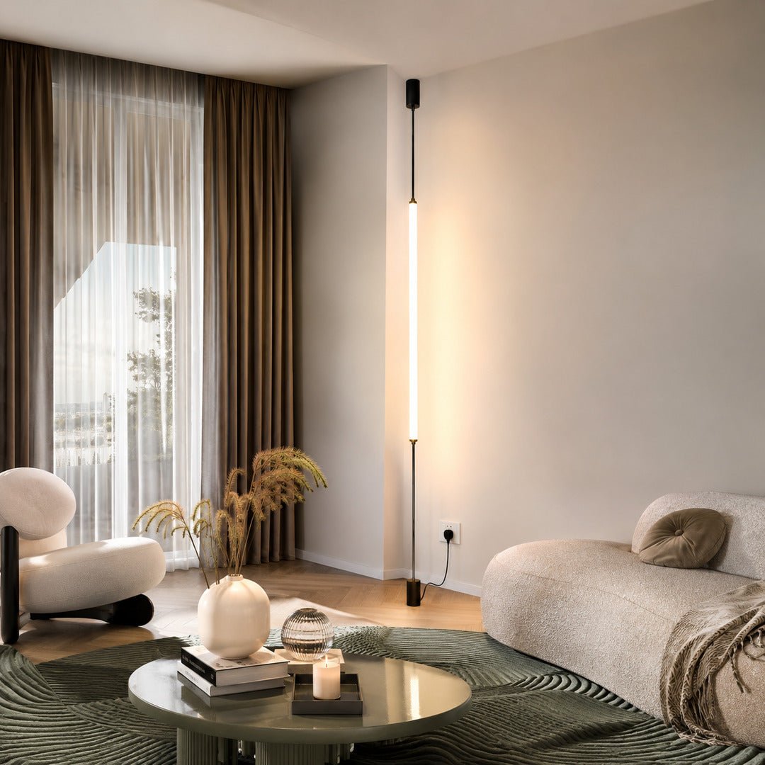 Black Stelo LED tube lamp running floor to ceiling beside a linen sofa in a minimalist living room