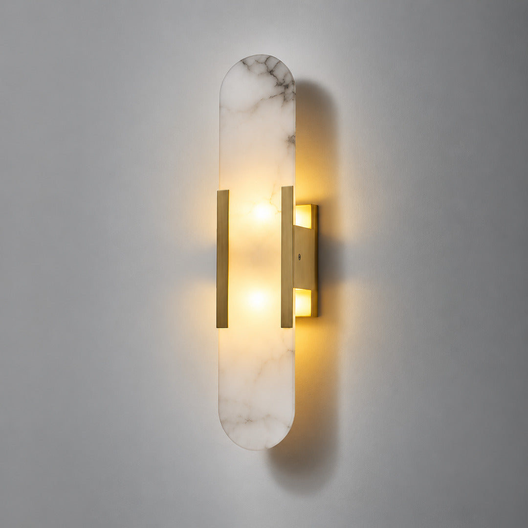 Warm light glowing up and down from the alabaster cylinder of the Stilo wall sconce