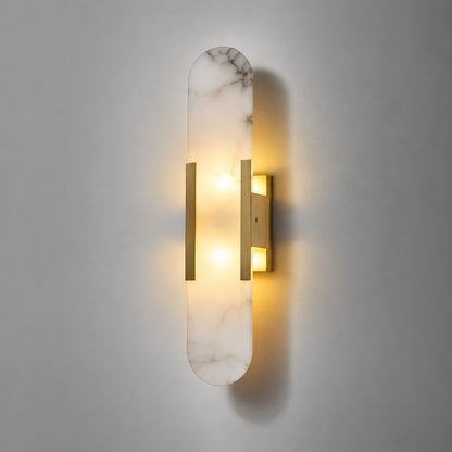 Warm light glowing up and down from the alabaster cylinder of the Stilo wall sconce